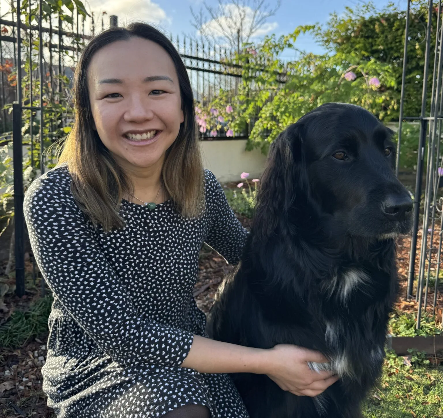 Whitney with Hope, her black dog companion, in a garden setting